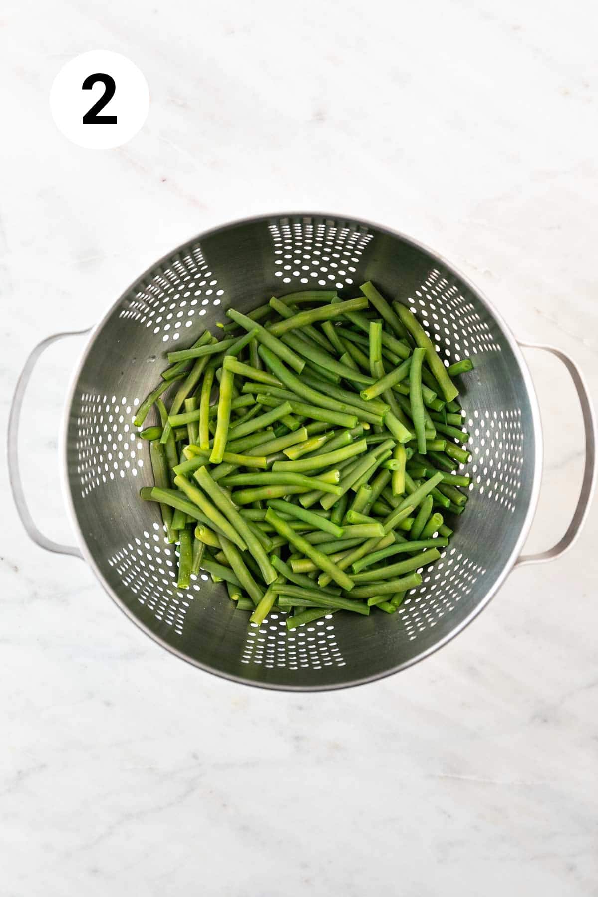 Blanched green beans in a colander.