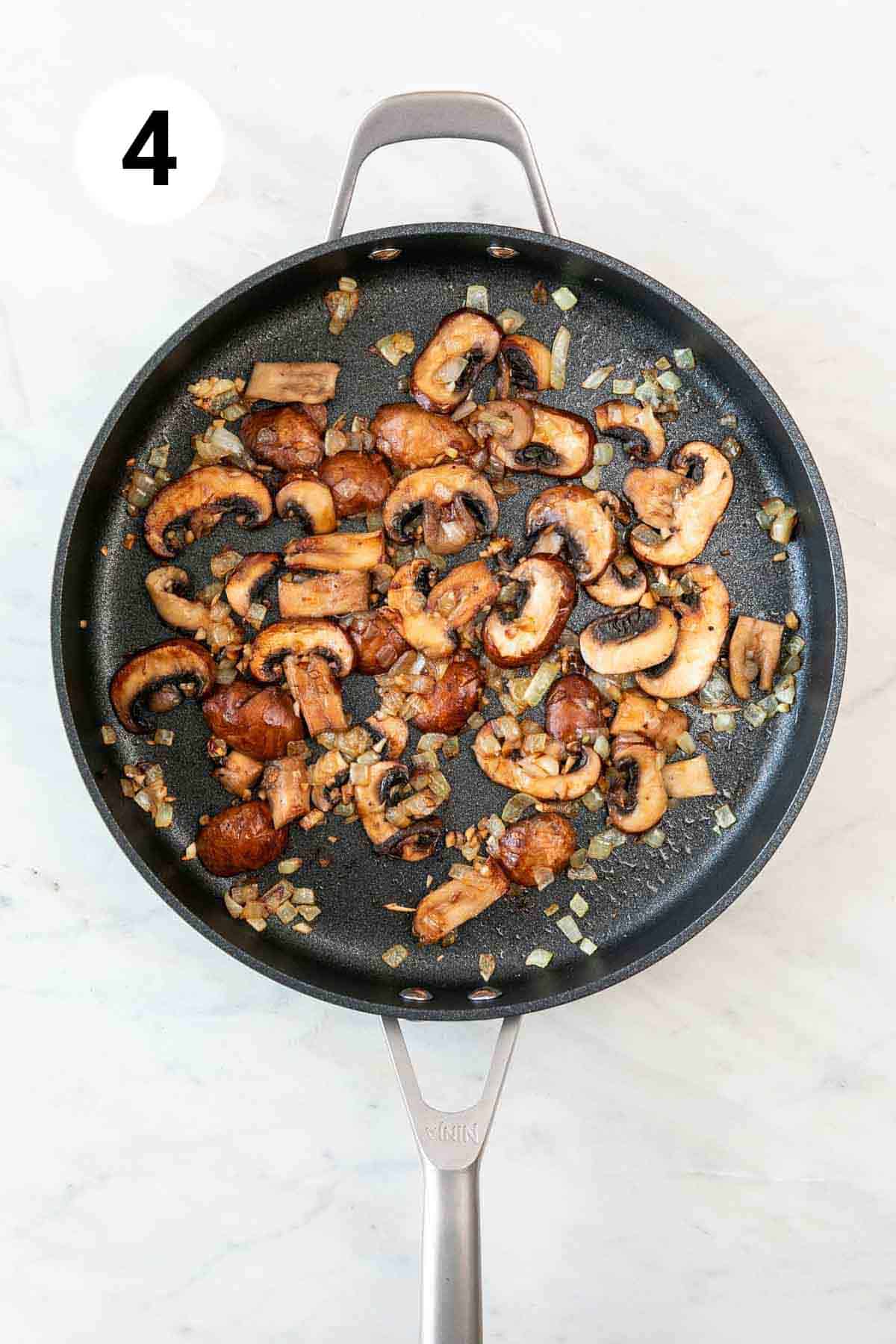 Onion, garlic, and mushrooms sautéed in a skillet.