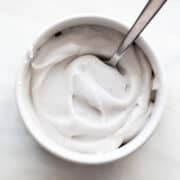Whipped vegan cream in a bowl with a spoon inside.