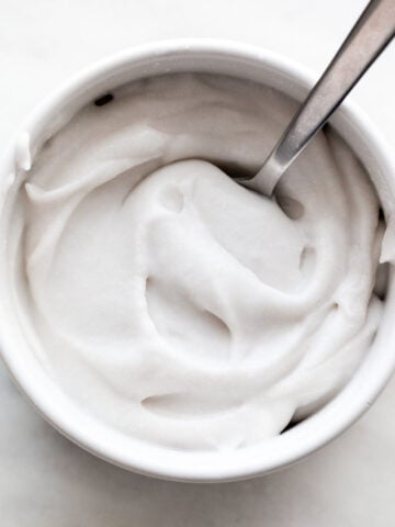 Whipped vegan cream in a bowl with a spoon inside.