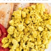 Tofu scramble served with bread and tomato slices on a plate.