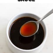 Spoon scooping vegan Worcestershire sauce from bowl.