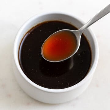 Spoon serving vegan Worcestershire sauce from bowl.
