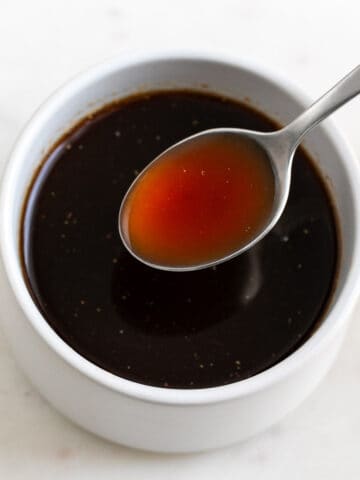 Spoon serving vegan Worcestershire sauce from bowl.