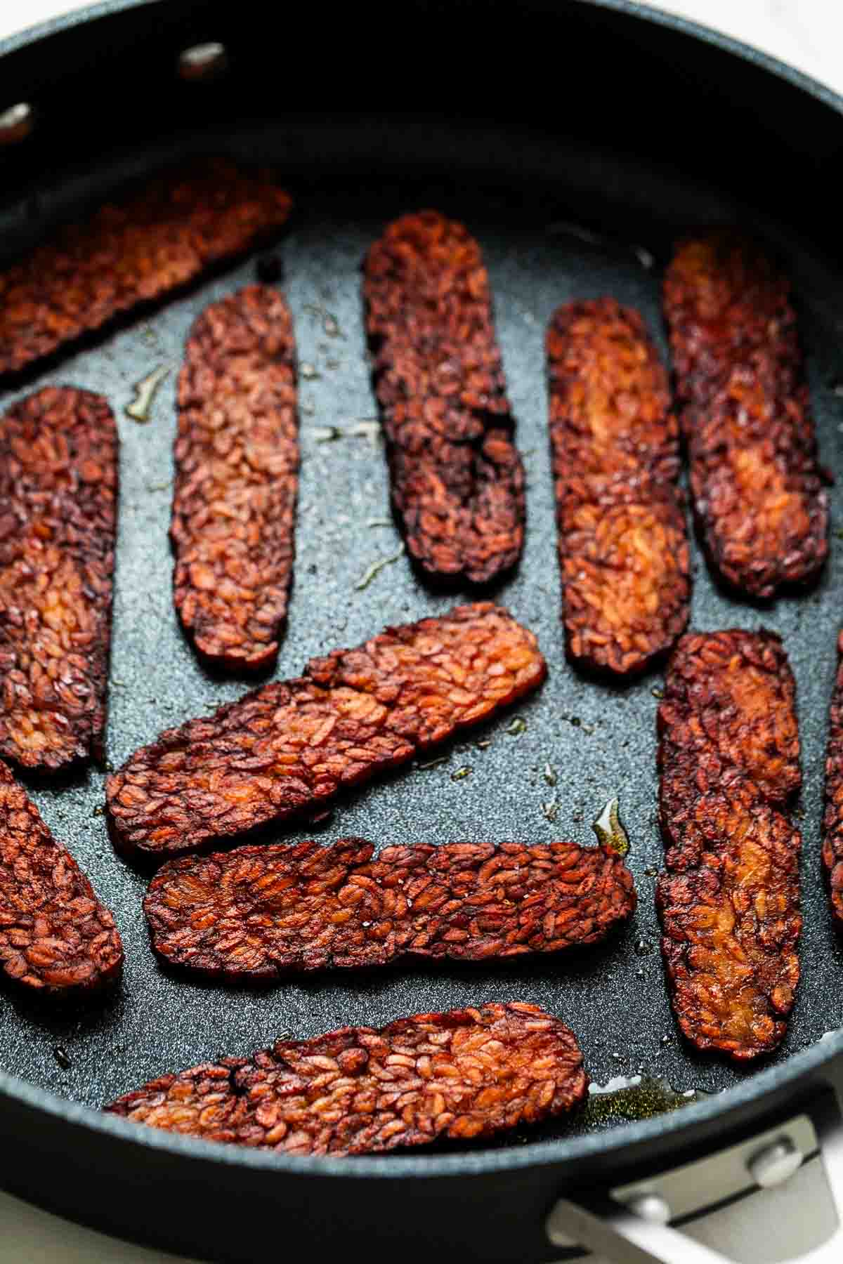 Cooked tempeh bacon in a large pan.