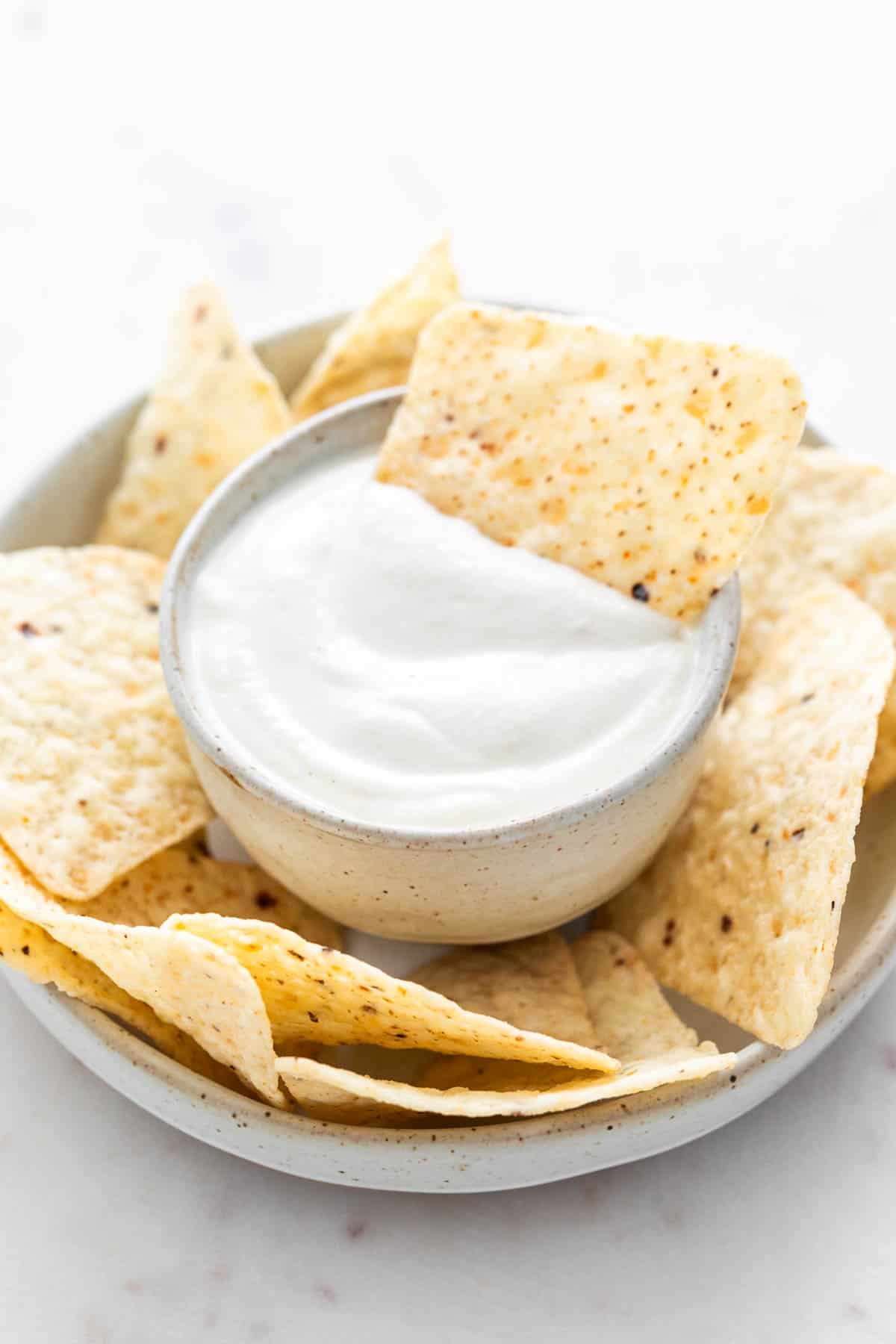Vegan sour cream topped with a tortilla chip for dipping.