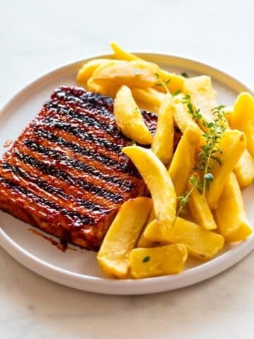 Tofu steak, fries, and thyme on a plate.