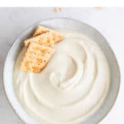 Vegan cashew cheese in bowl surrounded by crackers.