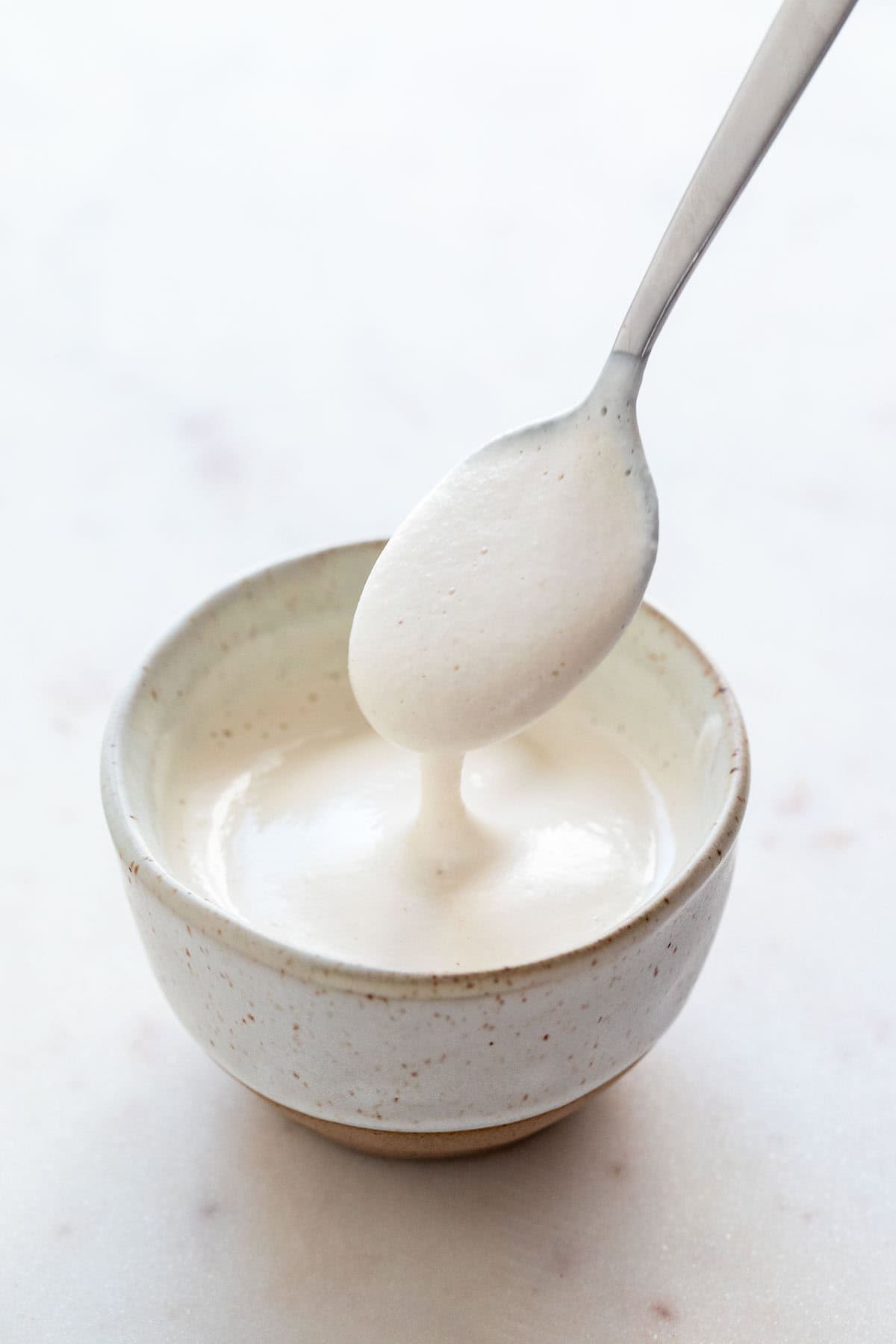 Spoon scooping vegan heavy cream substitute from bowl.