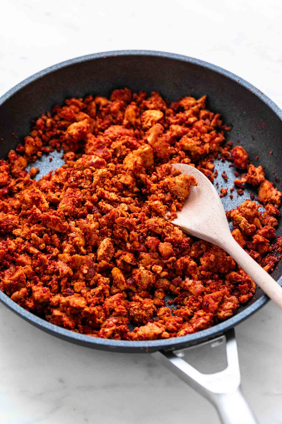 Skillet with vegan soy chorizo and a wooden spoon.
