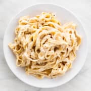 Vegan cashew alfredo pasta sprinkled with ground black pepper.