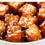 Sesame tofu cubes topped with sesame seeds and chopped chives.