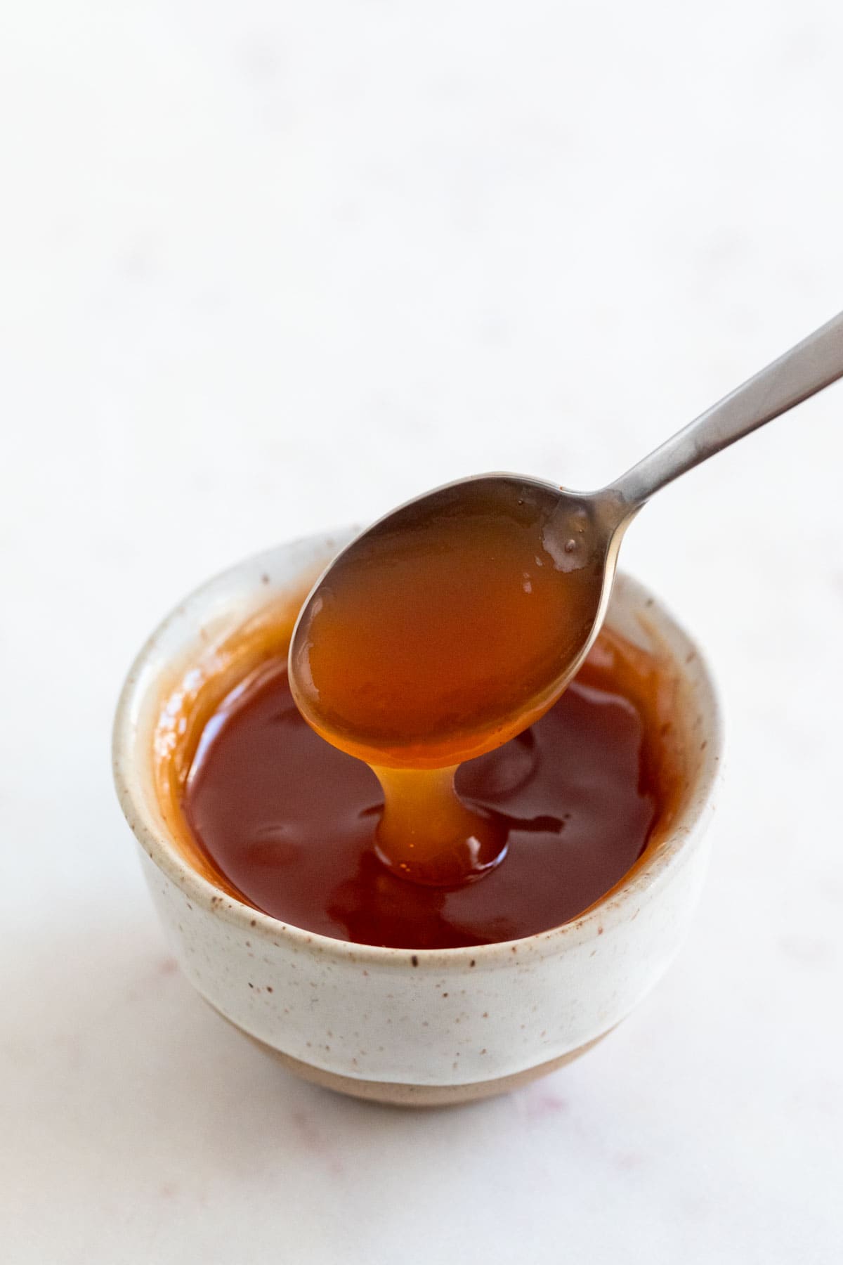 Spoon dipping into bowl of sweet and sour sauce.