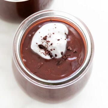 Vegan chocolate pudding in a glass, adorned with whipped cream and chocolate curls.