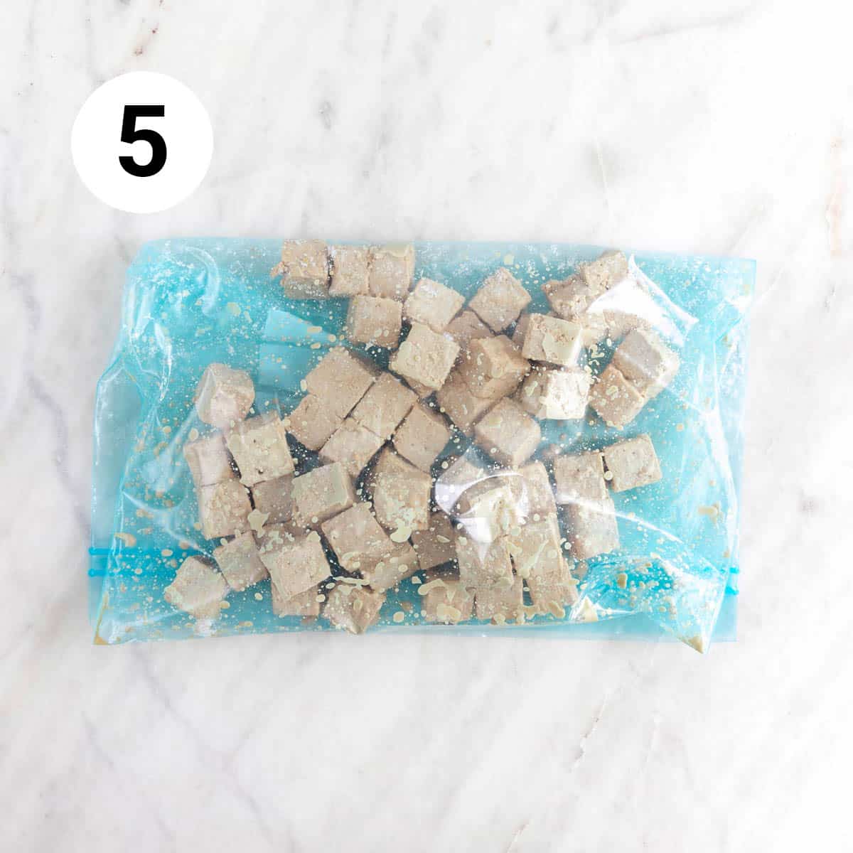 Tofu cubes with soy sauce covered with cornstarch in a large ziplock bag.