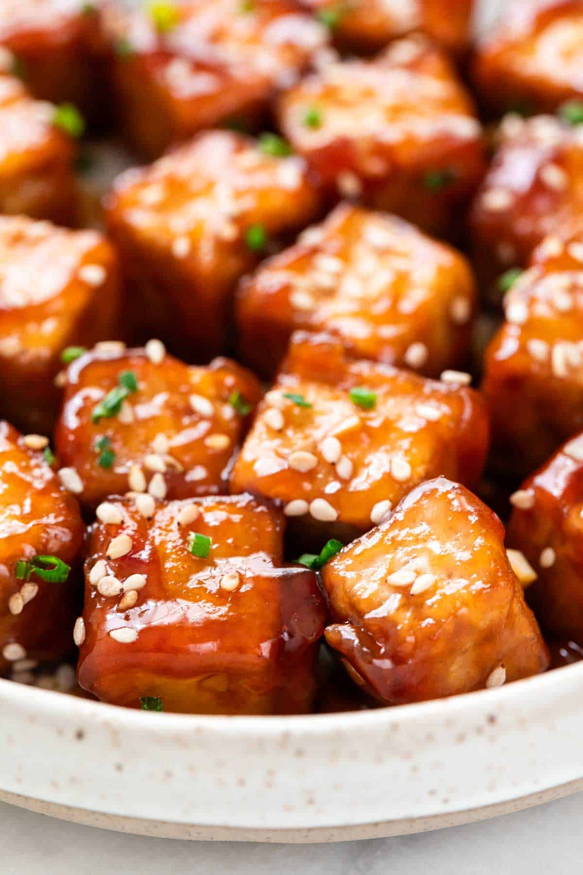 Sesame tofu cubes garnished with sesame seeds and chives.