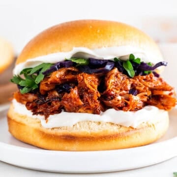 Vegan BBQ jackfruit pulled pork sandwich topped with vegan mayo and vegetables.