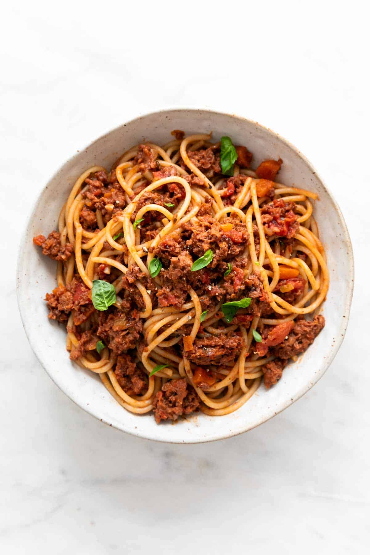 Vegan bolognese sauce mixed with spaghetti in a bowl.