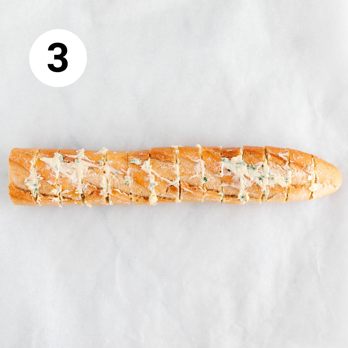 Sliced baguette spread with butter mixture.