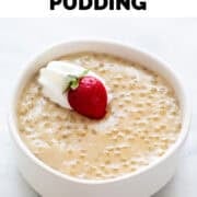 Bowl of vegan tapioca pudding topped with vegan whipped cream and a strawberry.