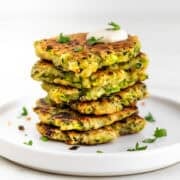 Vegan zucchini fritters served with a dollop of vegan sour cream and topped with parsley.