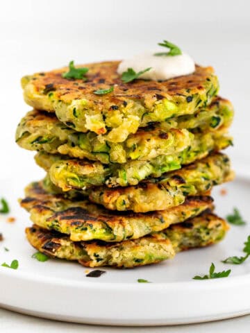 Vegan zucchini fritters served with a dollop of vegan sour cream and topped with parsley.