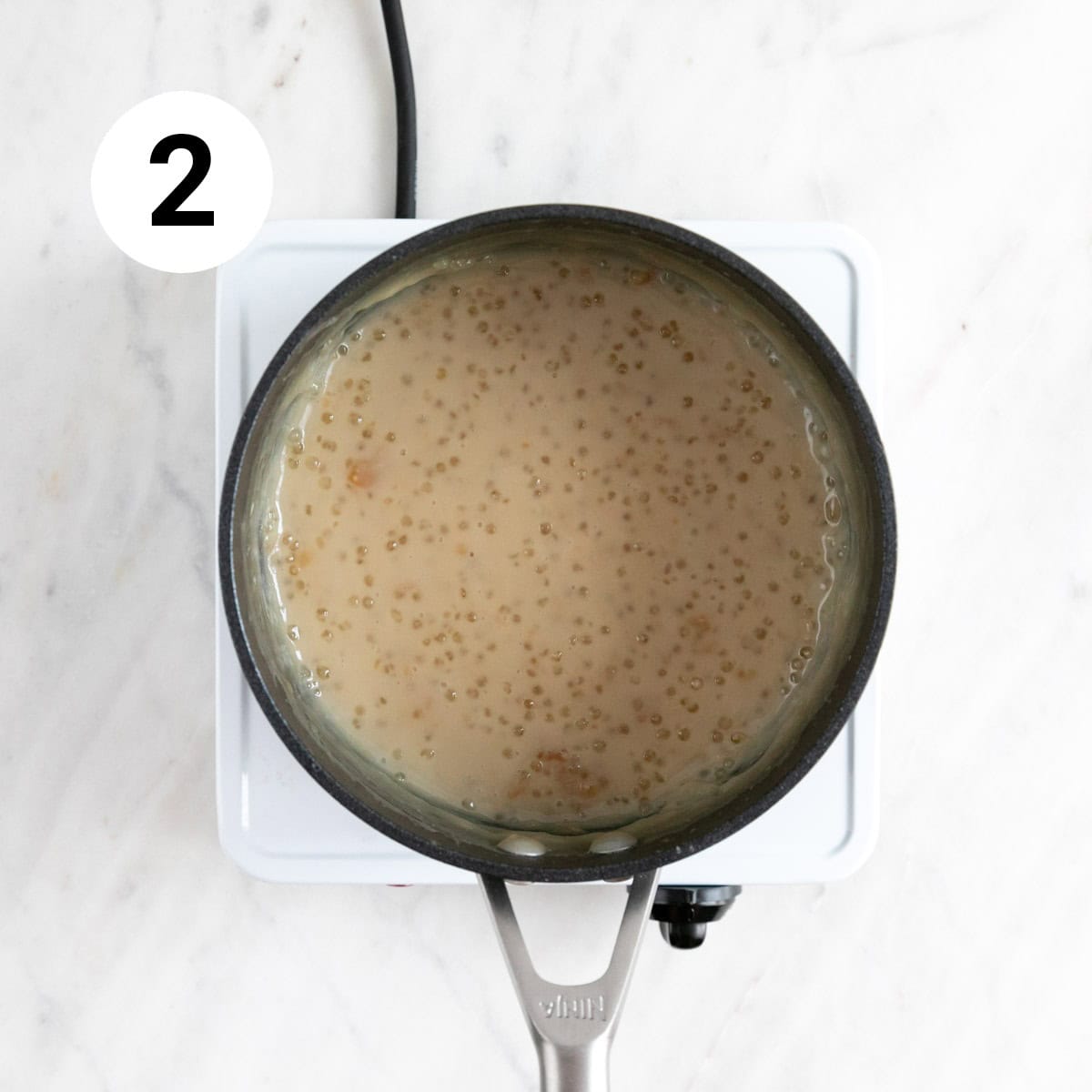 Vegan tapioca pudding cooking in a saucepan before adding vegan butter and vanilla.