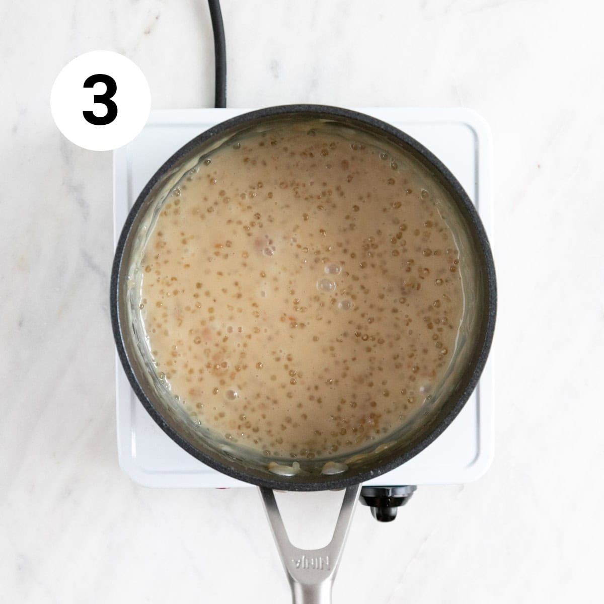 Vegan tapioca pudding cooking in a saucepan after adding vegan butter and vanilla.