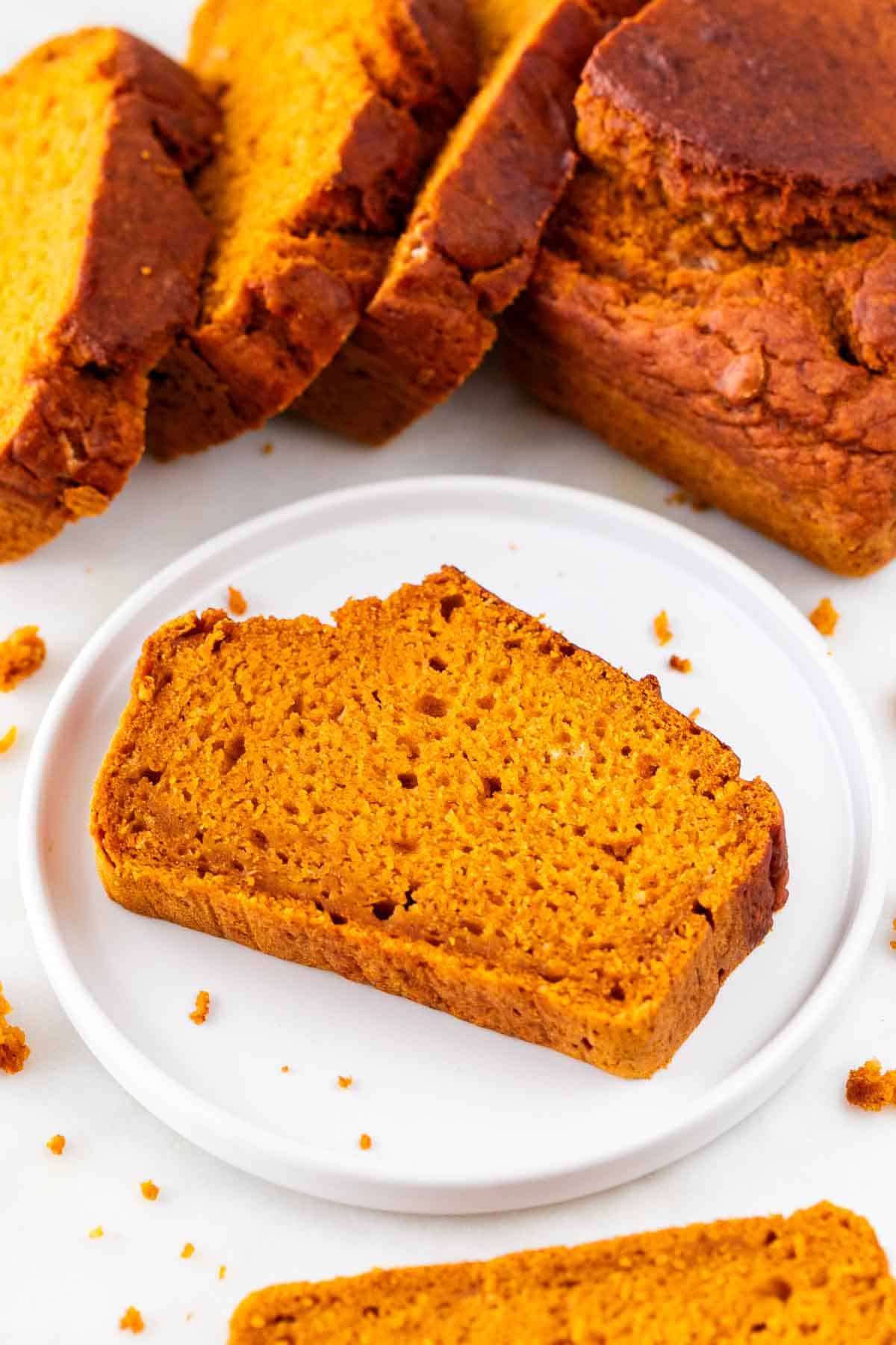 Sliced vegan pumpkin bread and a single slice on a plate.