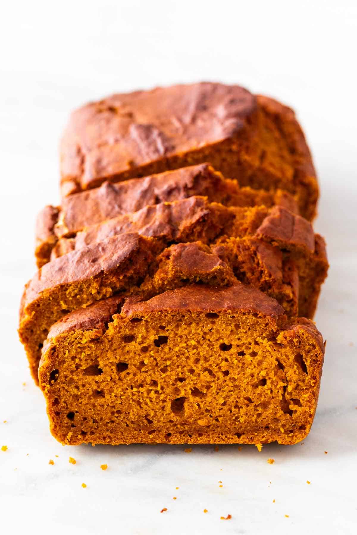 Sliced vegan pumpkin bread on a marble background.