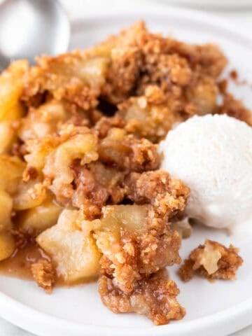 Plate of vegan apple crisp, vegan vanilla ice cream, and spoon.