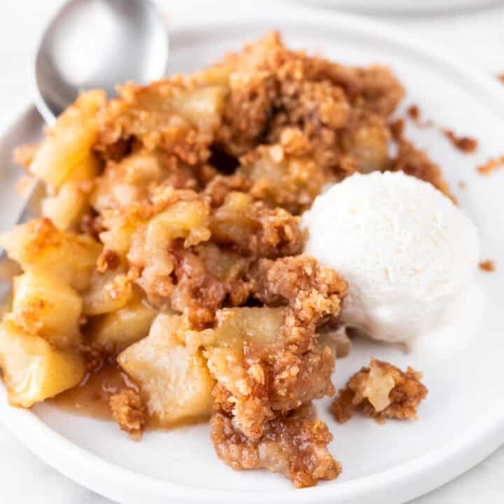 Plate of vegan apple crisp, vegan vanilla ice cream, and spoon.