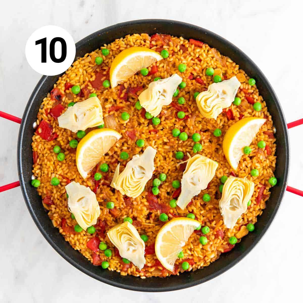 Fully cooked vegan paella with lemon wedges on top.