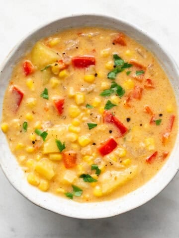 Vegan potato and corn chowder served in a bowl with parsley on top.