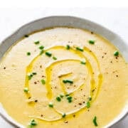 Vegan potato leek soup in a bowl topped with olive oil, black pepper, and chives.