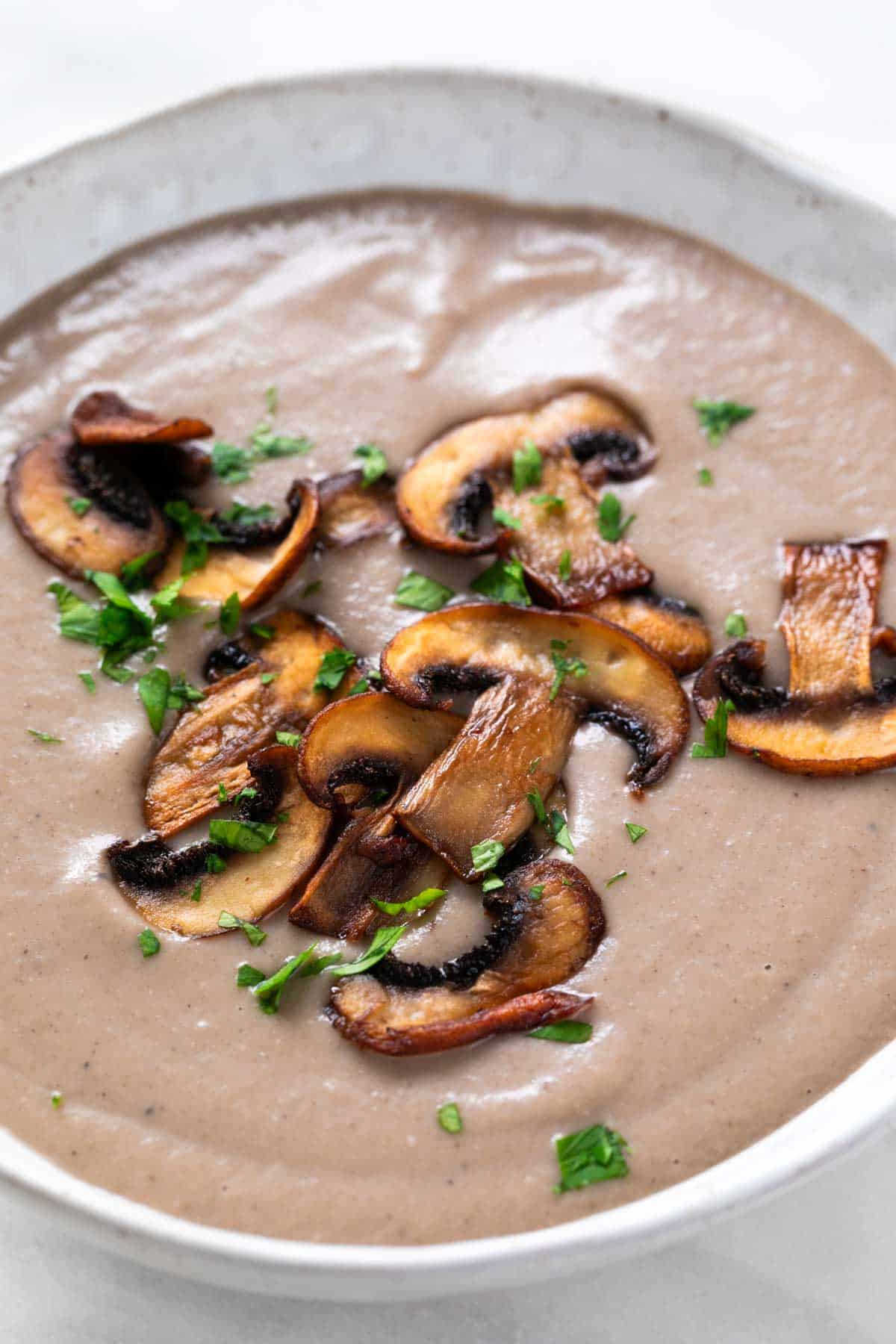 Vegan mushroom soup with sautéed mushrooms and parsley on top.