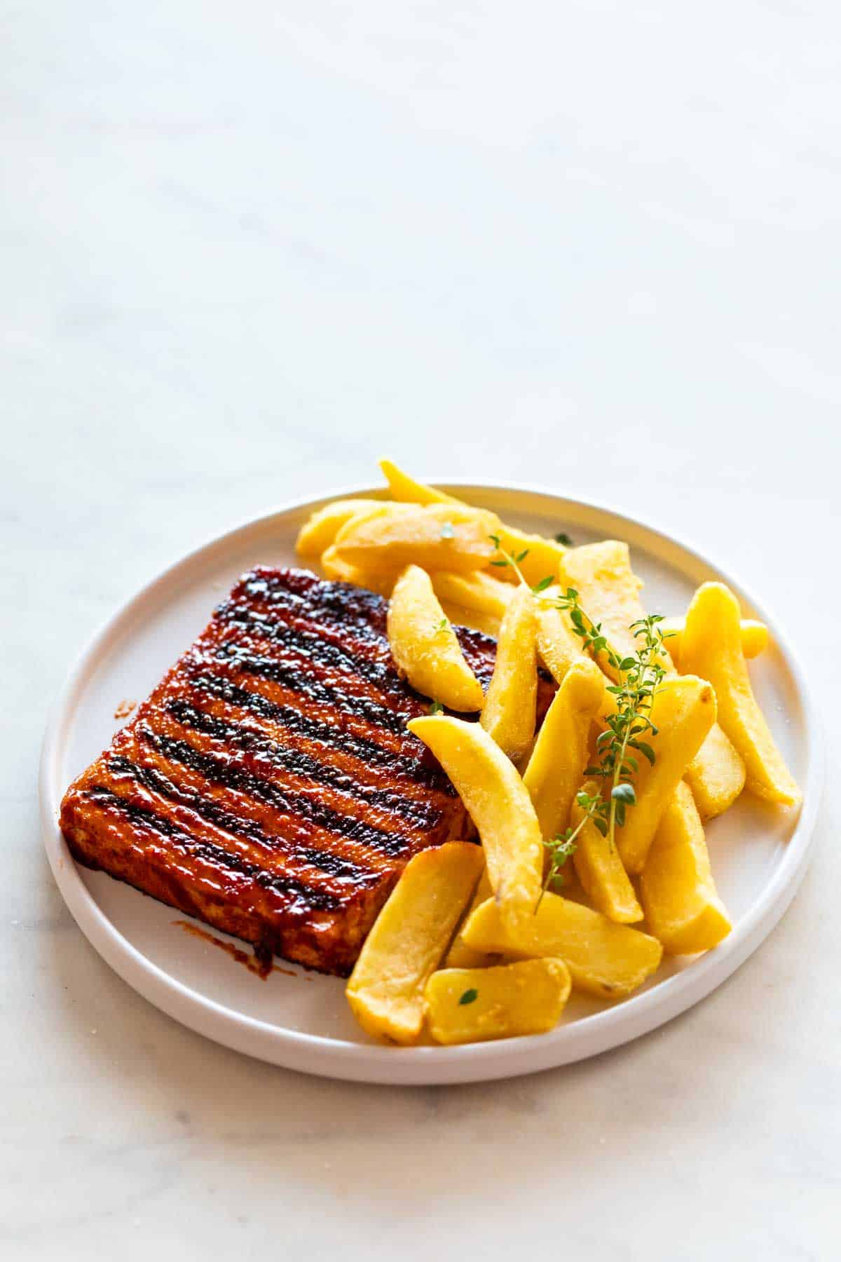 Plate of tofu steak, fries, and thyme.