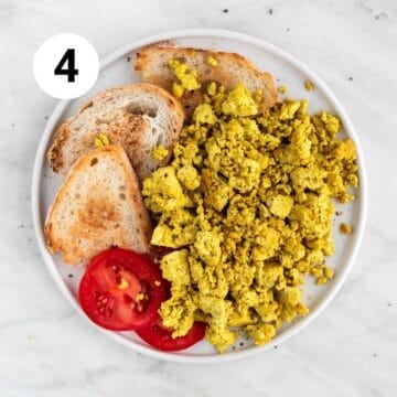 Toasted bread and tomato slices alongside scrambled tofu on a plate.