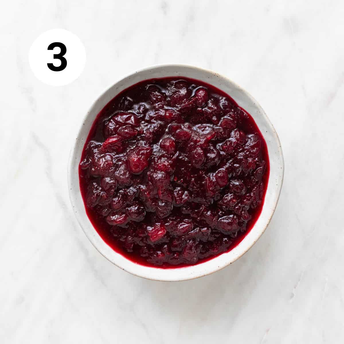 Cooked vegan cranberry sauce in a bowl before cooling and thickening.