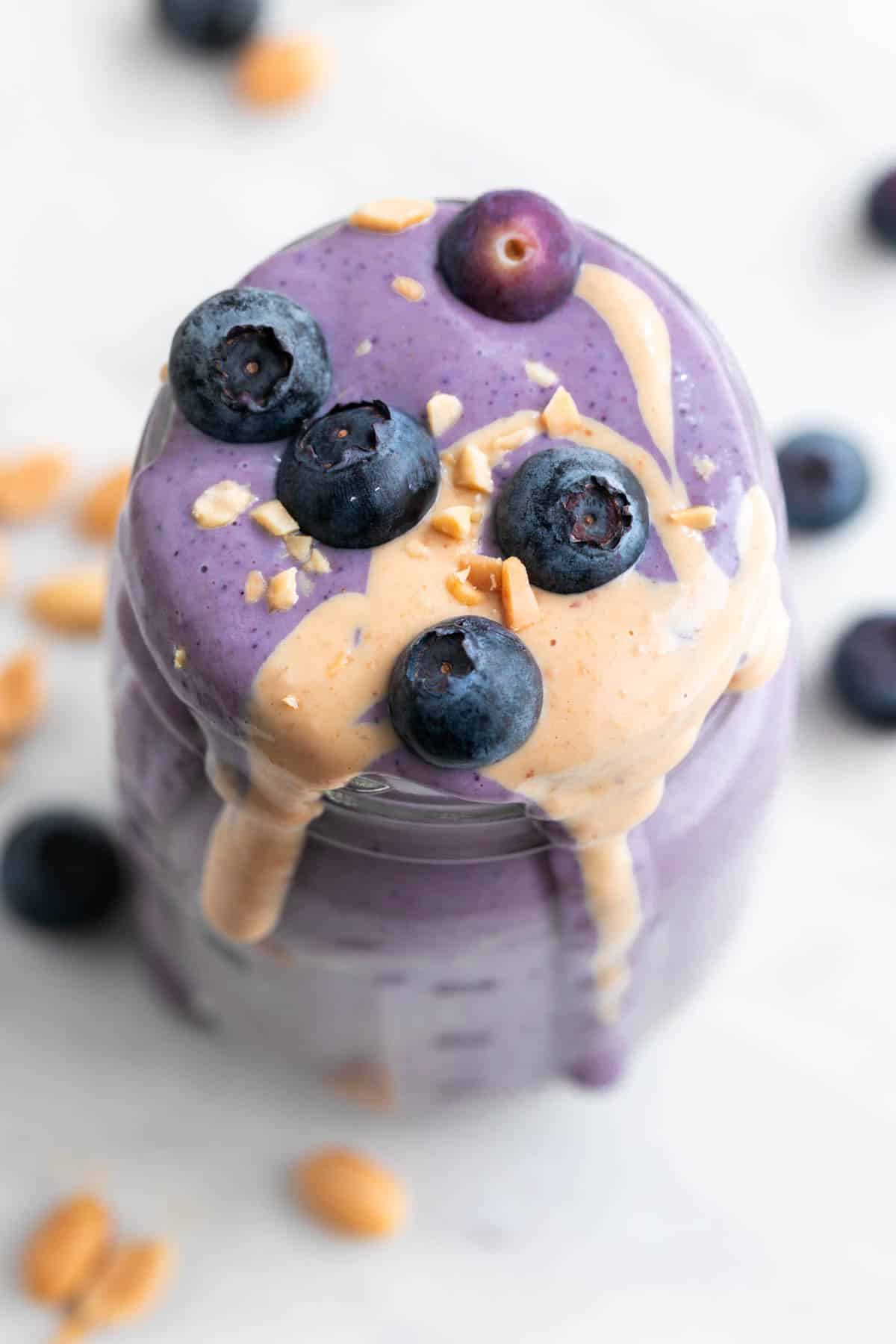 Silken tofu smoothie in a jar, topped with blueberries, peanut butter, and chopped peanuts.