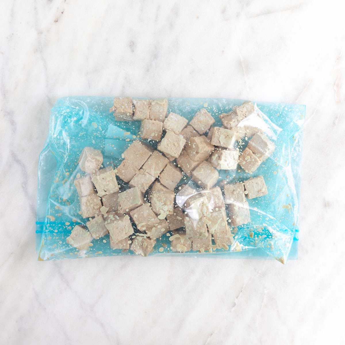 Tofu cubes with soy sauce covered with cornstarch in a large ziplock bag.