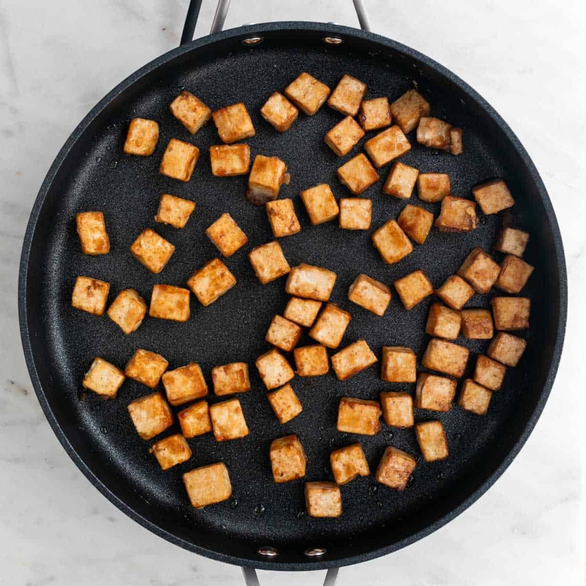 Sautéed tofu cubes in a skillet.