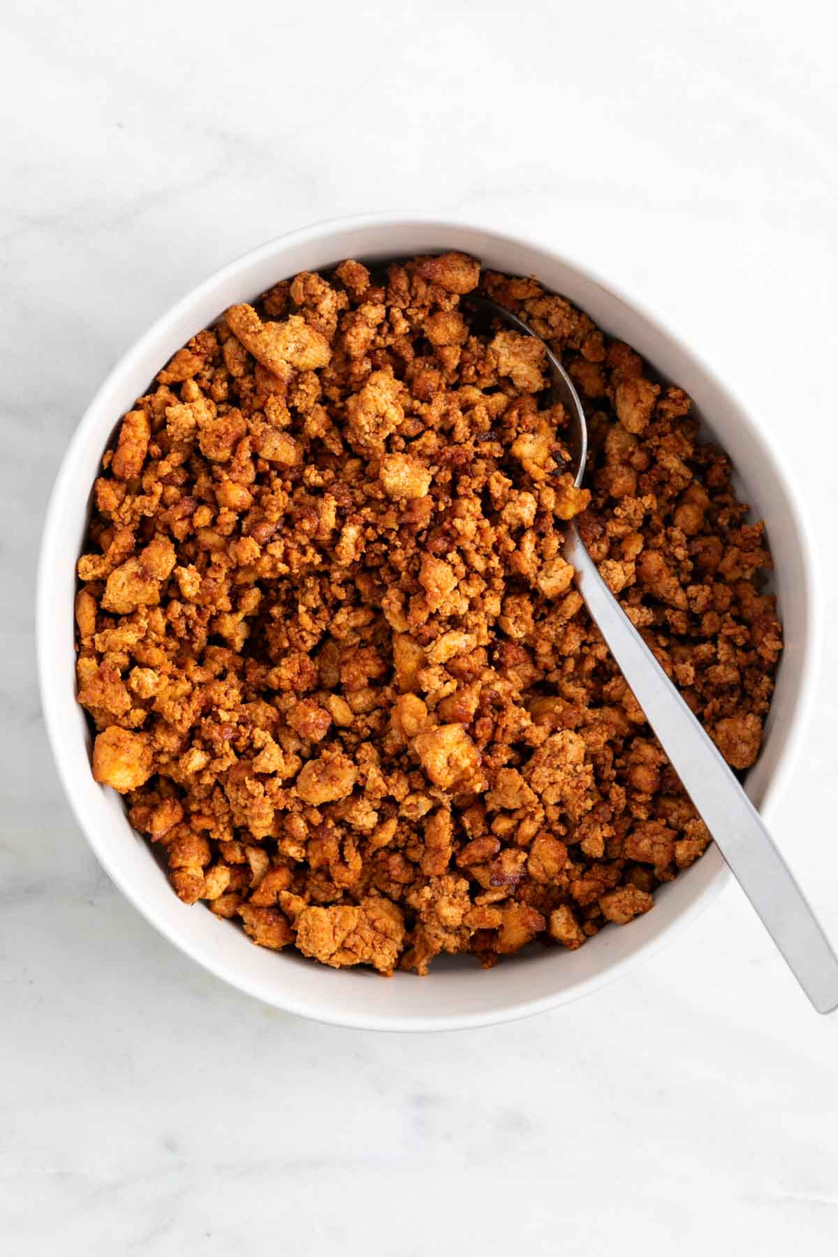 Crumbled tofu ground beef in a bowl with a spoon.