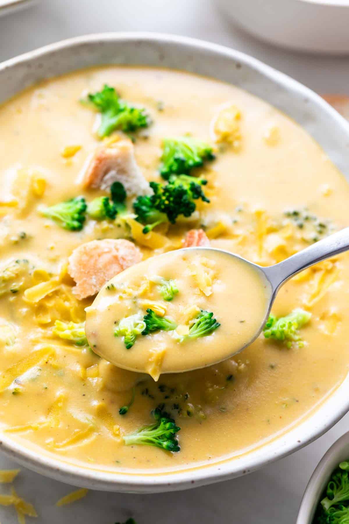 Spoon taking vegan broccoli cheddar soup from a bowl.