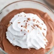 Serving glass of tofu chocolate mousse topped with vegan whipped cream and chocolate shavings.