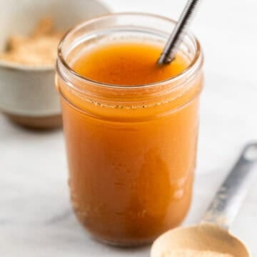 Vegan beef broth in a jar and vegan beef bouillon powder on a spoon.