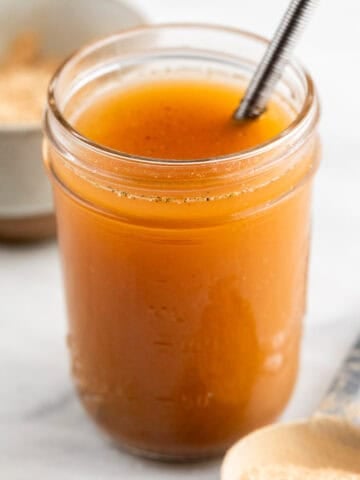 Vegan beef broth in a jar and vegan beef bouillon powder on a spoon.