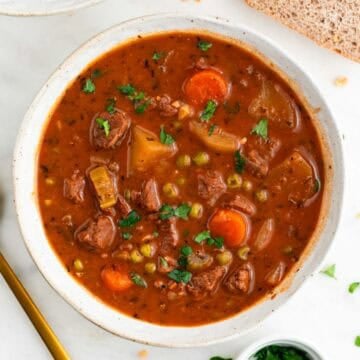 Vegan beef stew served in a bowl with bread and parsley around it.