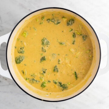 Blended soup in a large pot with broccoli and vegan cheese before cooking.