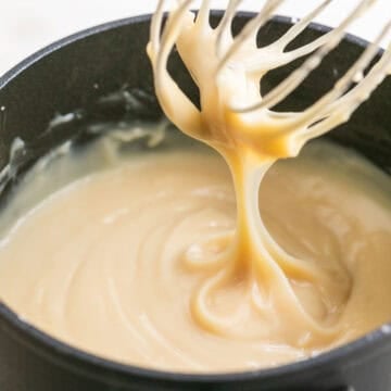 A whisk dripping vegan custard from a saucepan.